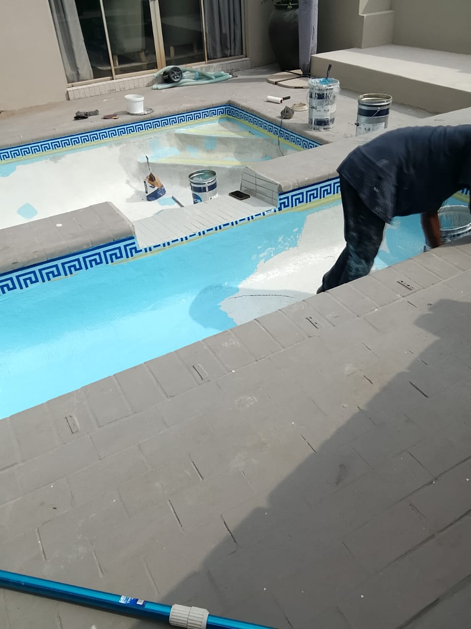 worker resurfacing two part swimming pool