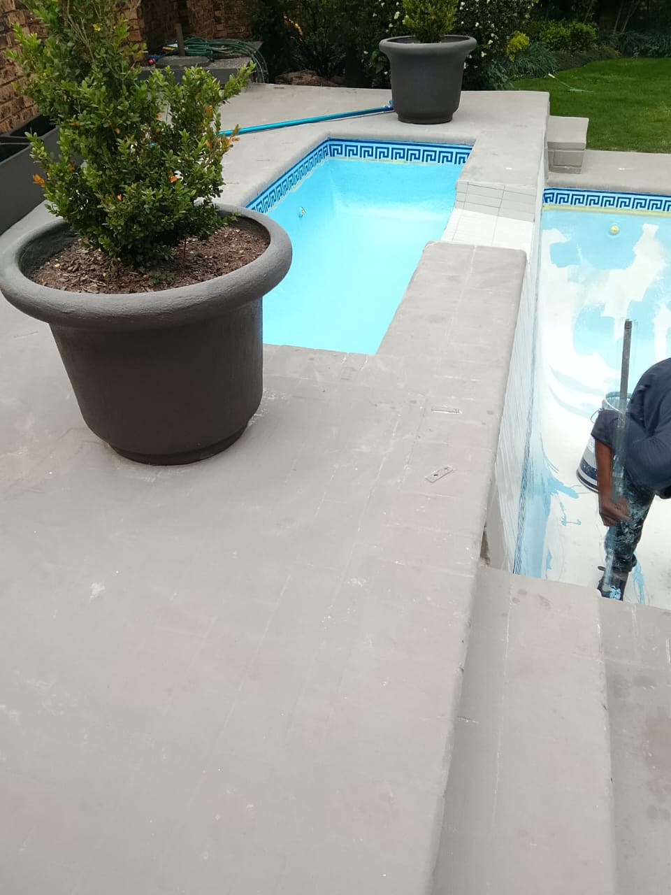 worker resurfacing two part swimming pool