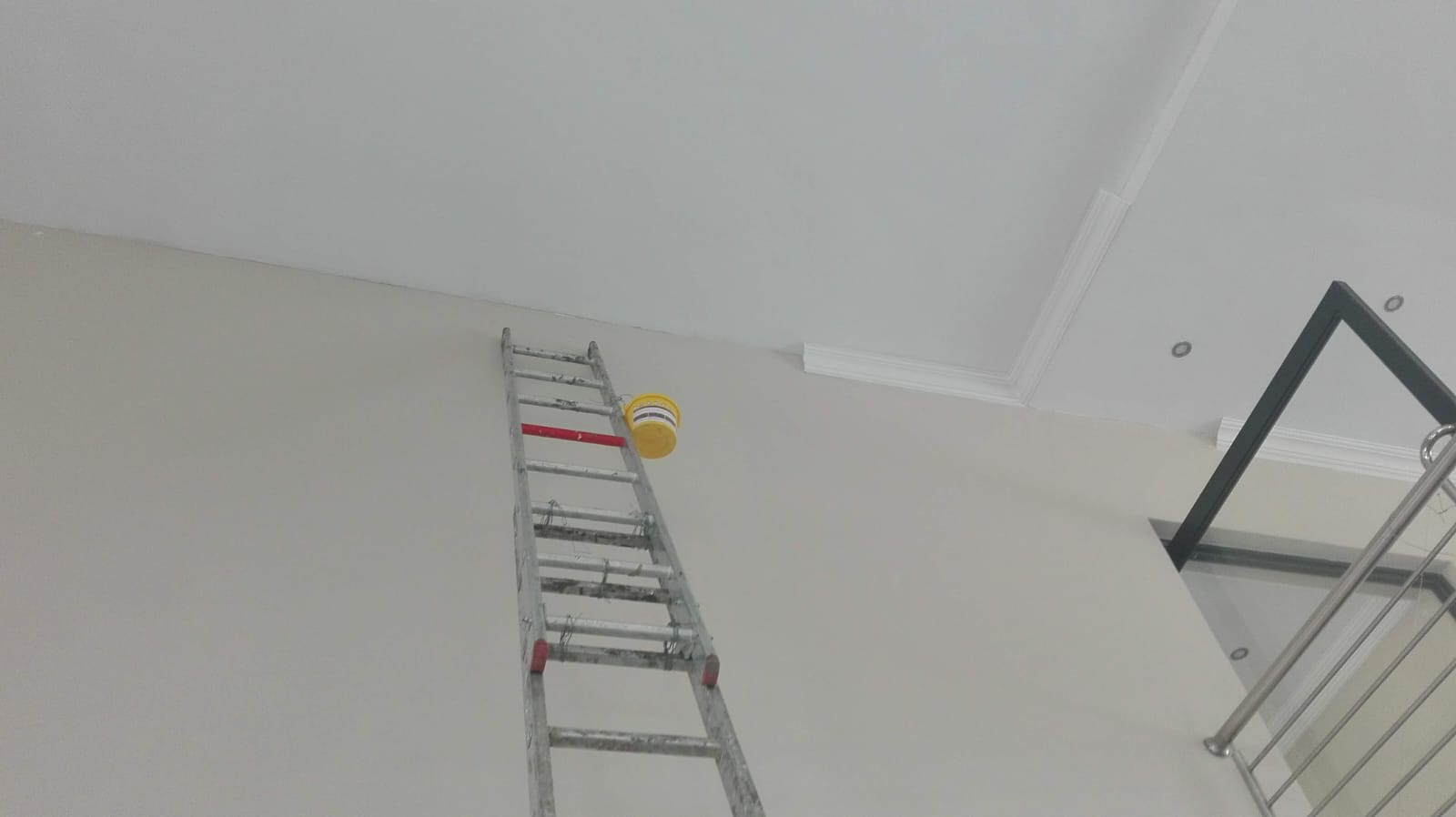 interior wall in the process of being painted white. Ladder propped against wall